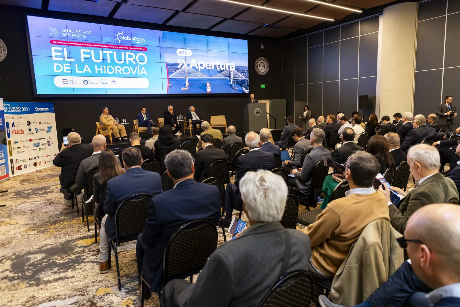 Público en el salón de la Bolsa de Cereales frente a la pantalla de apertura del Seminario
