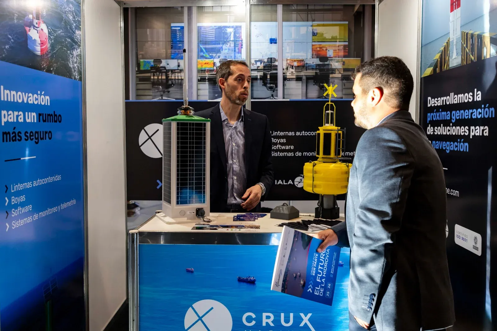 Dos visitantes conversando en el stand de una empresa de tecnología portuaria